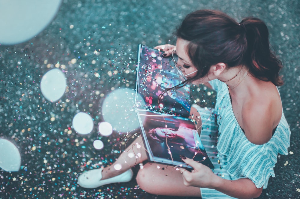 woman opening book with glitter 